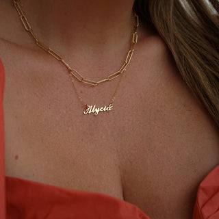 A gold plated necklace in Carrie font, with the name Alycia, on a woman