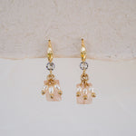 Gold earrings with pearl-like beads on a light background