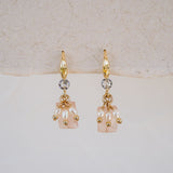 Gold earrings with pearl-like beads on a light background