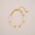 Gold and pearl bracelet on a beige background