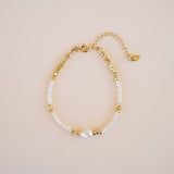 Gold and pearl bracelet on a beige background