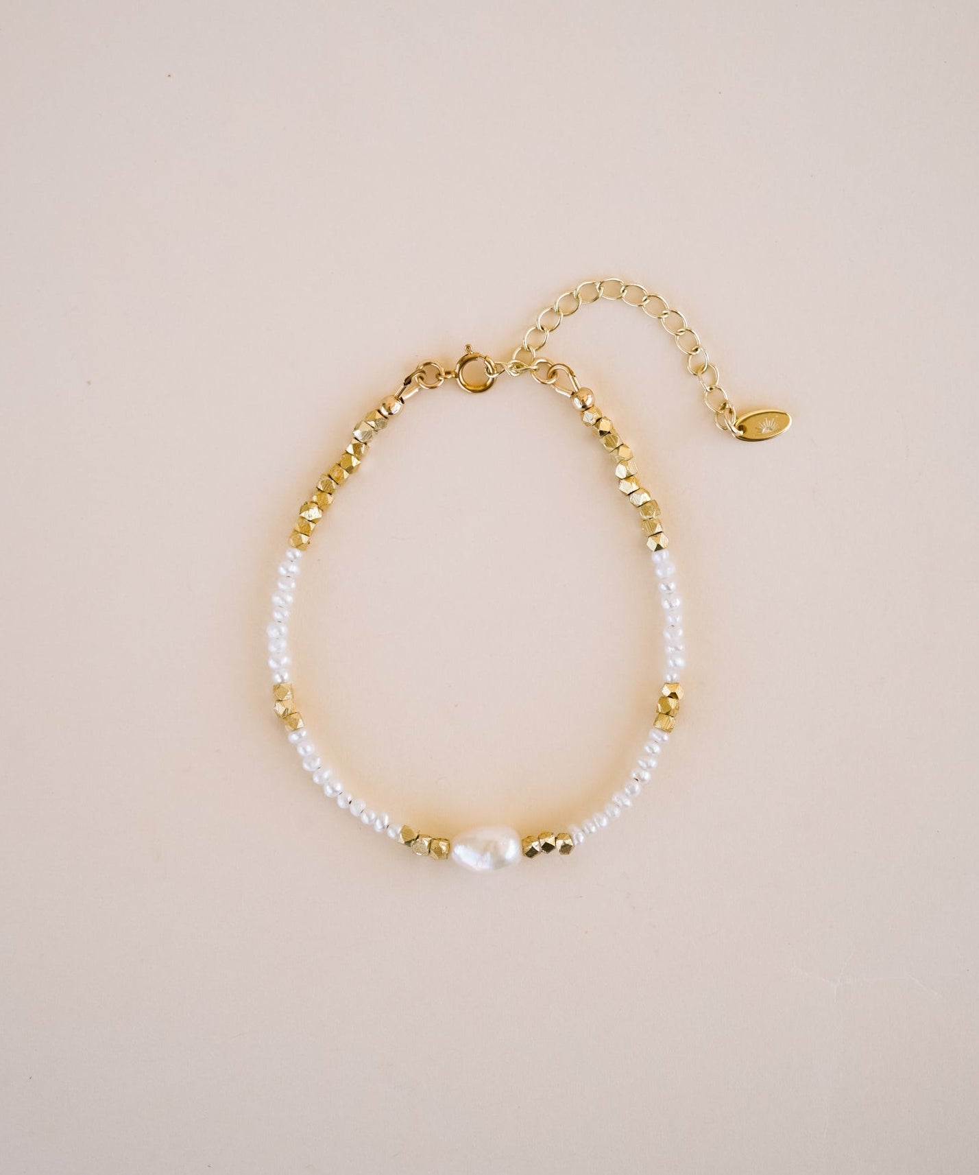 Gold and pearl bracelet on a beige background