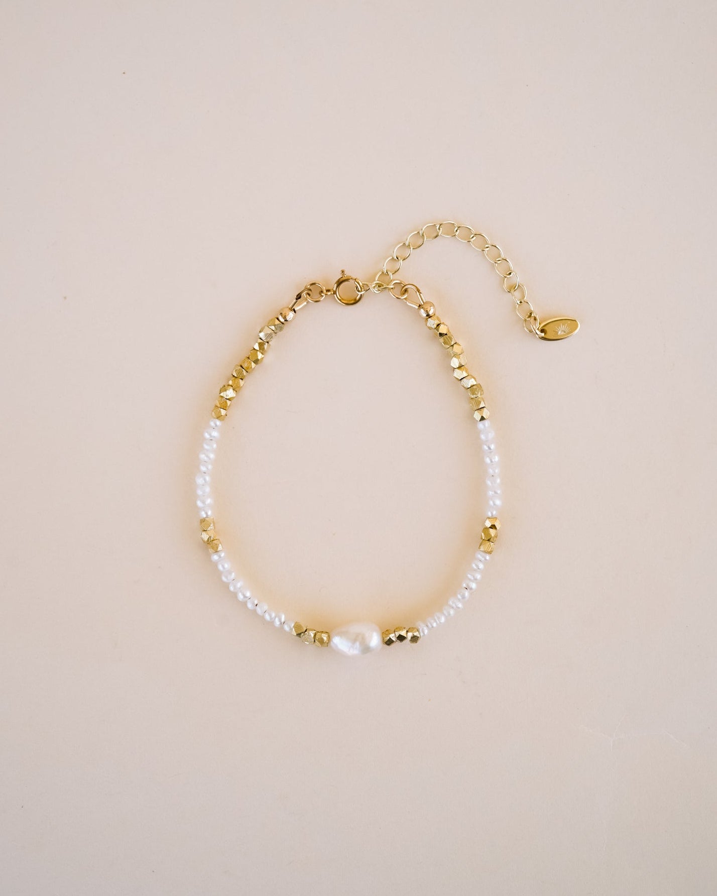 Gold and pearl bracelet on a beige background