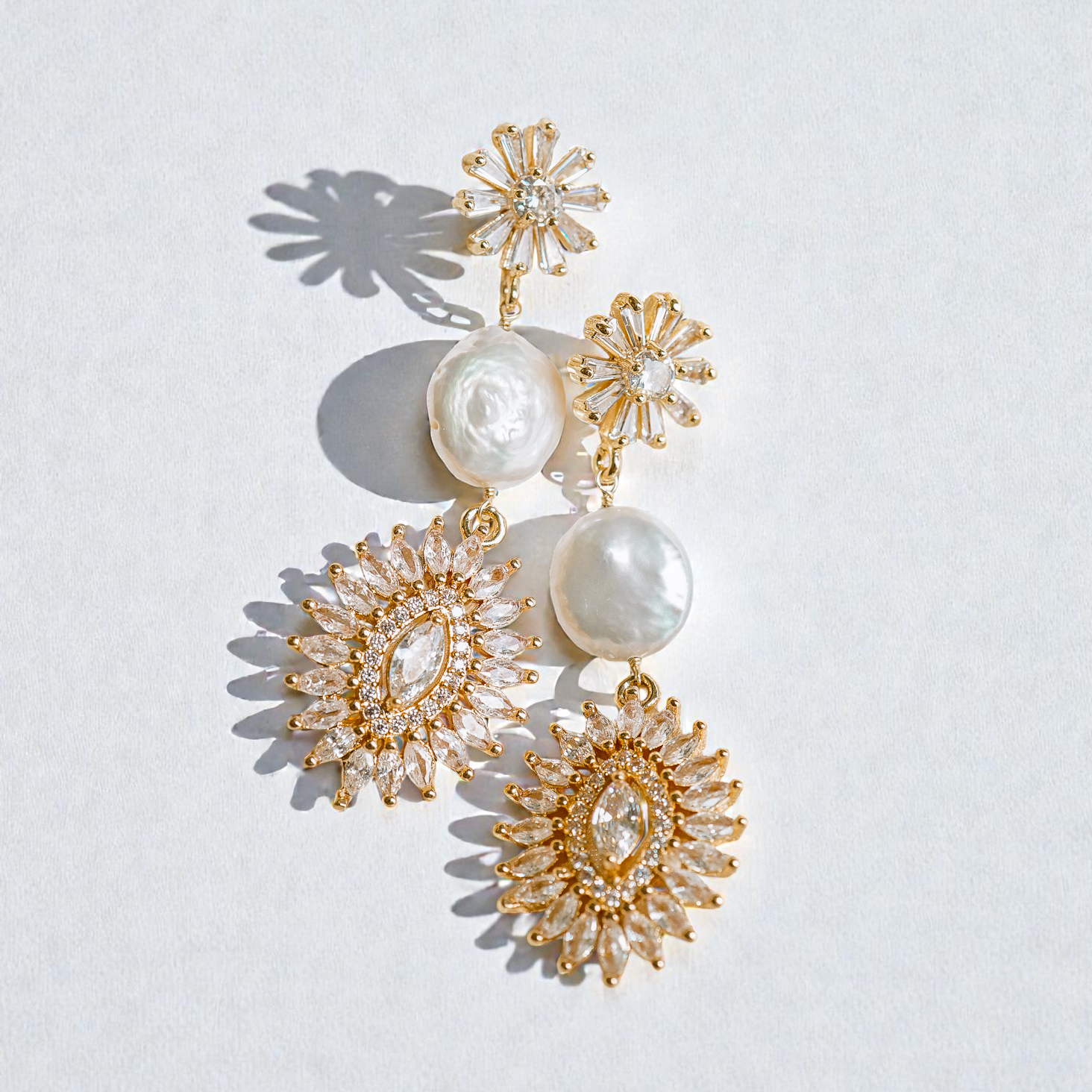 Gold and pearl earrings on a light gray background