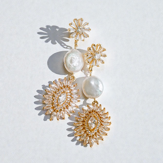 Gold and pearl earrings on a light gray background