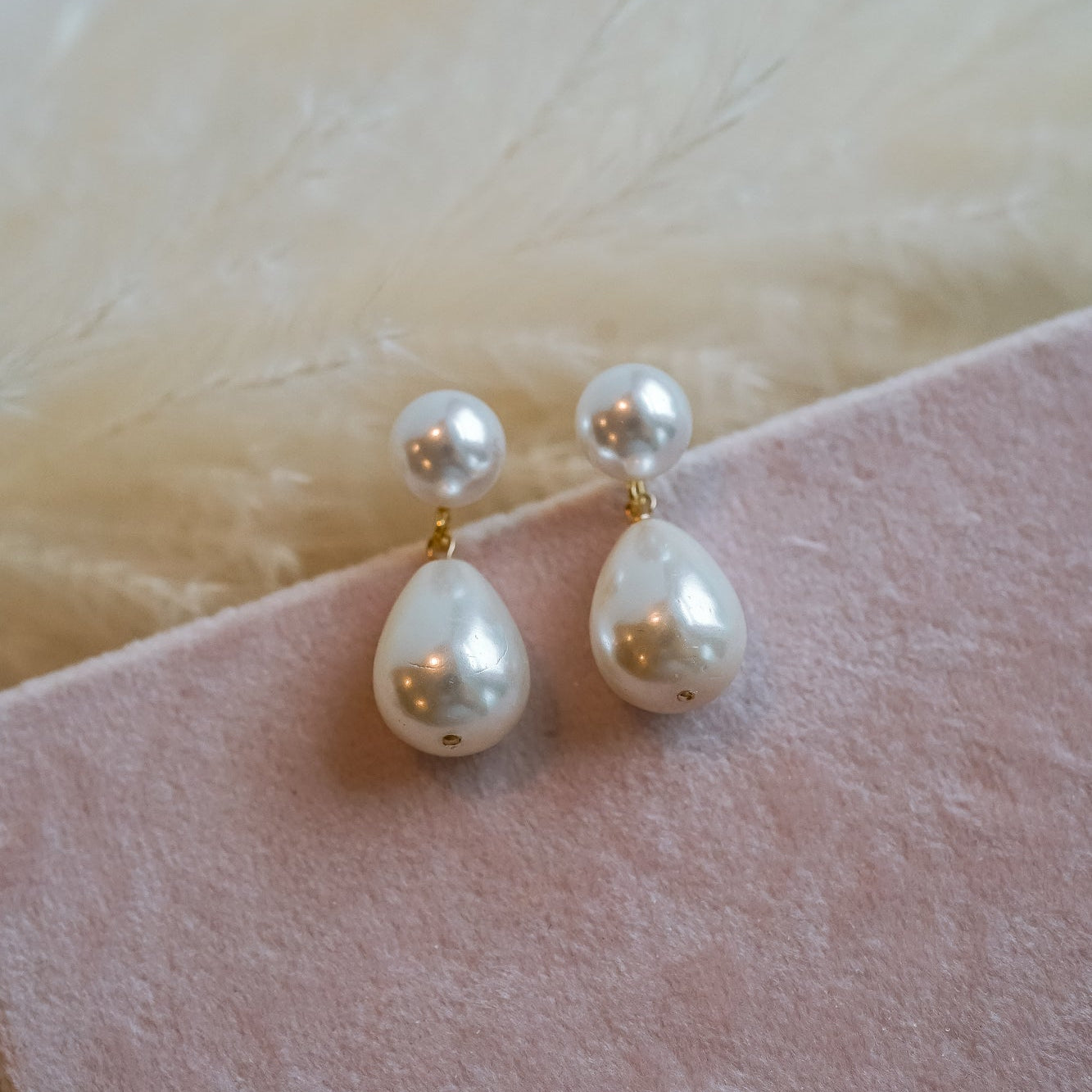 Pearl earrings on a pink fabric background