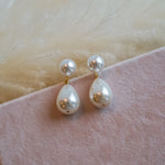 Pearl earrings on a pink fabric background