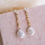 Pearl and crystal drop earrings on a pink surface
