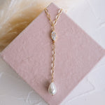 Gold necklace with a pearl pendant on a pink jewelry box