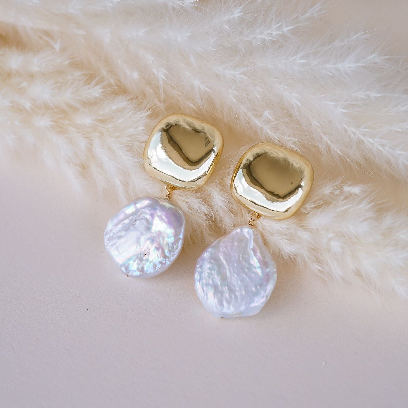 Gold earrings with pearl gemstones on a fur surface
