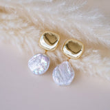 Gold earrings with pearl gemstones on a fur surface